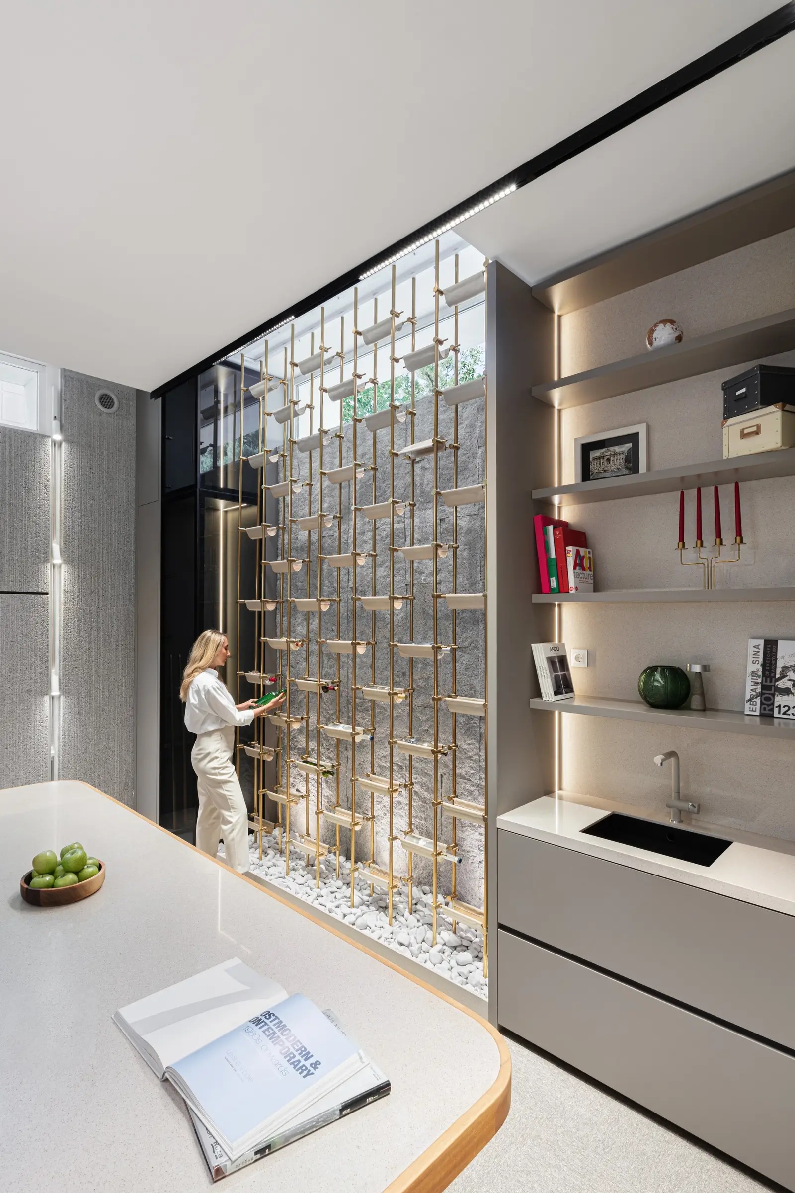 Rough stone wall behind brass shelving and a kitchenette